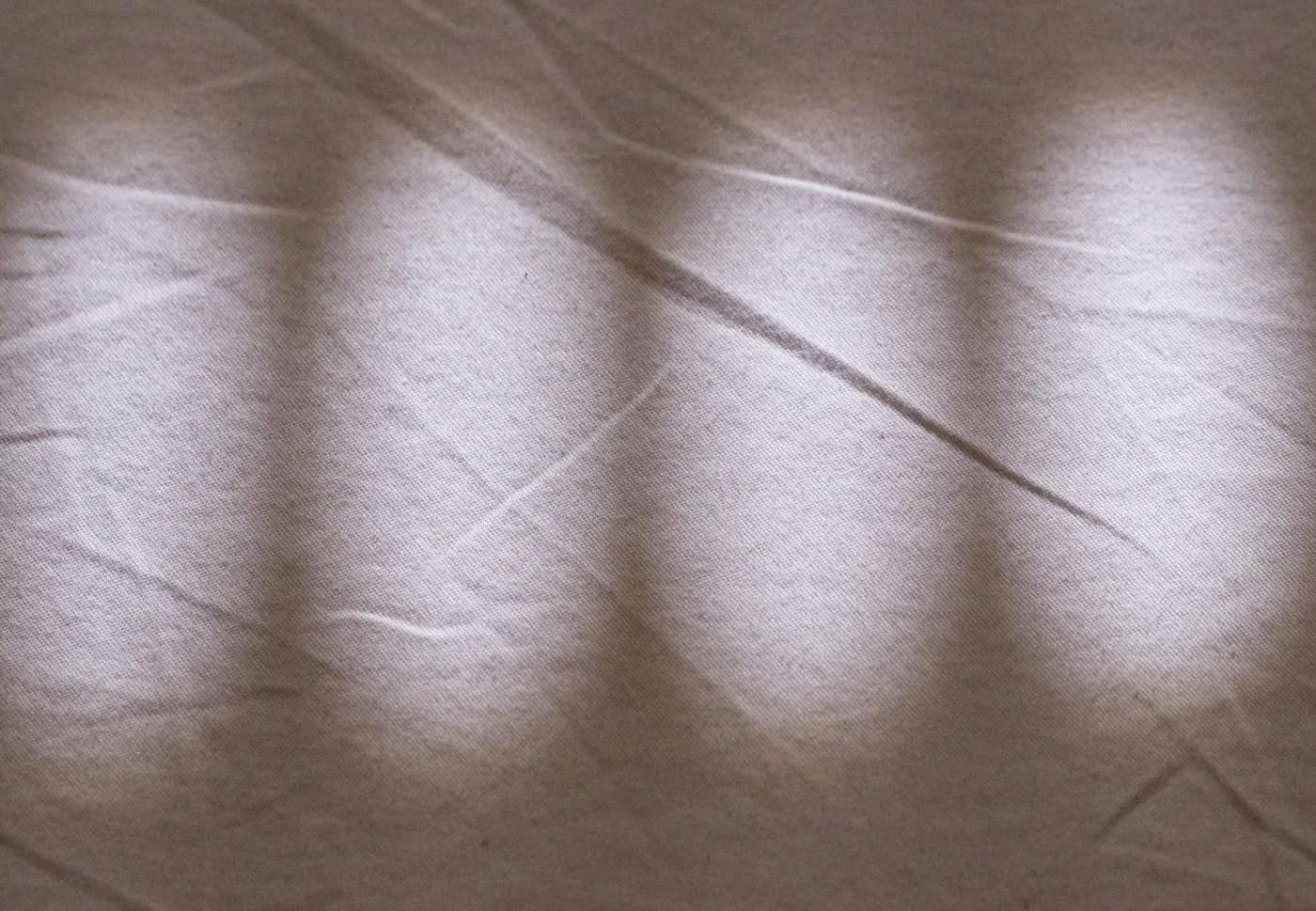 Drap de lin froissé traversé par la lumière d'une fenêtre